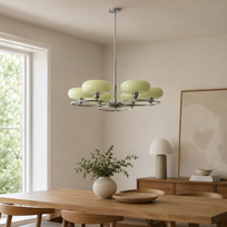 A modern multi-light chandelier with six pale green glass shades and a chrome ring, hanging in a minimalist dining room with a wooden table and chairs.