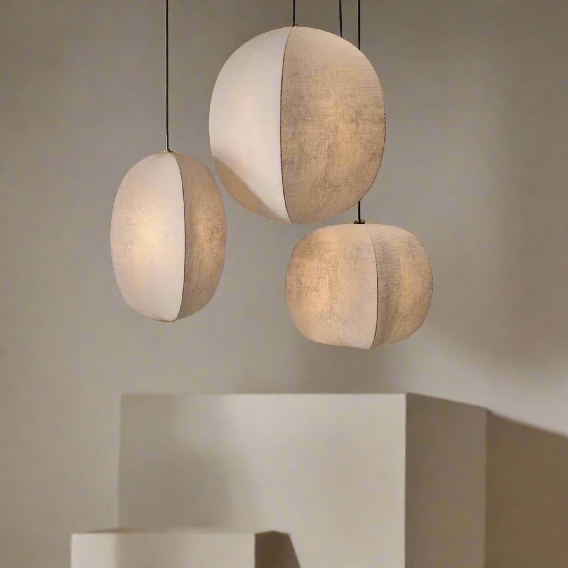 Three spherical pendant lights hanging against a neutral wall.