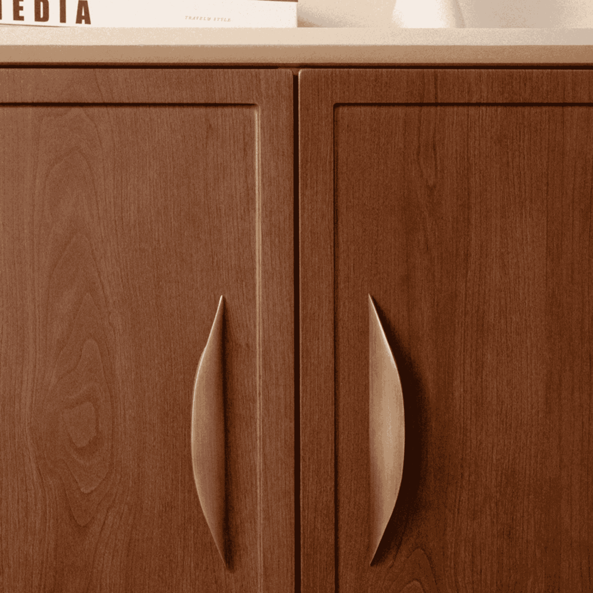 Close-up of wooden cabinet doors with handles on a countertop.