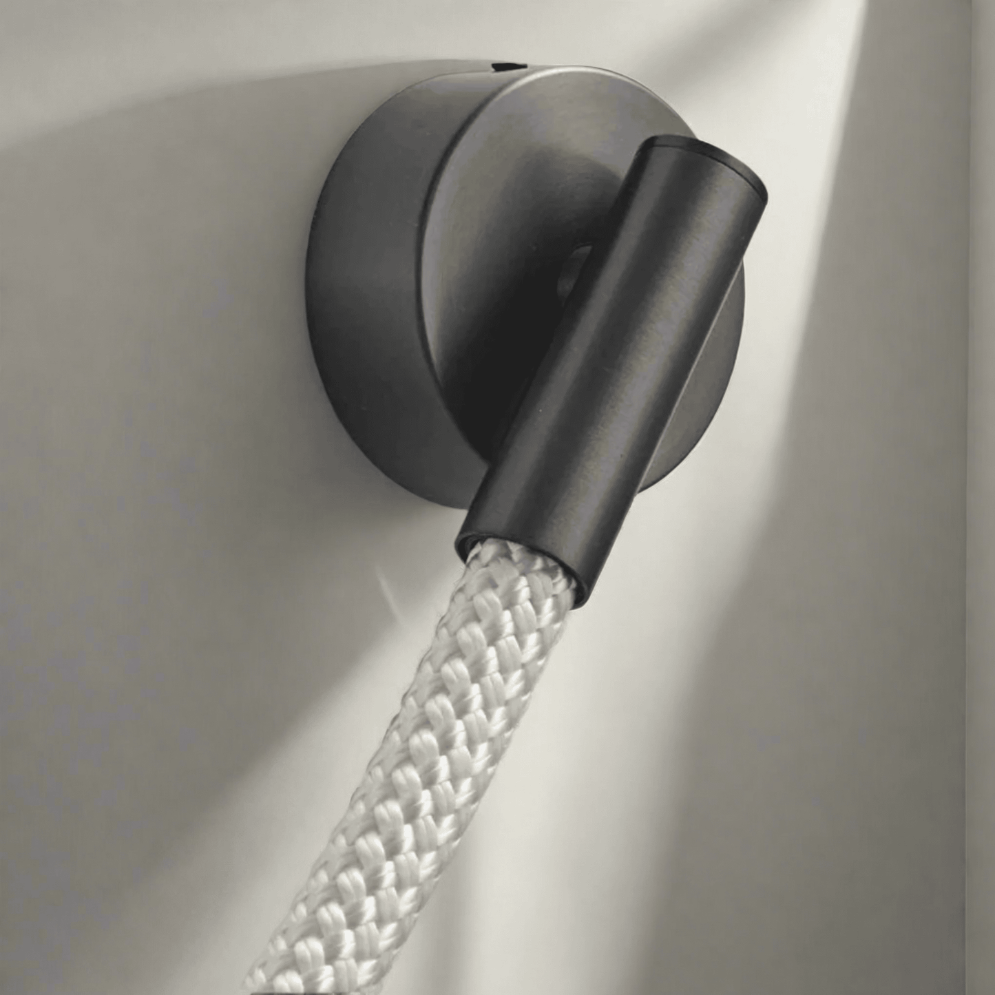 Black wall light fixture with a flexible hose on a neutral background