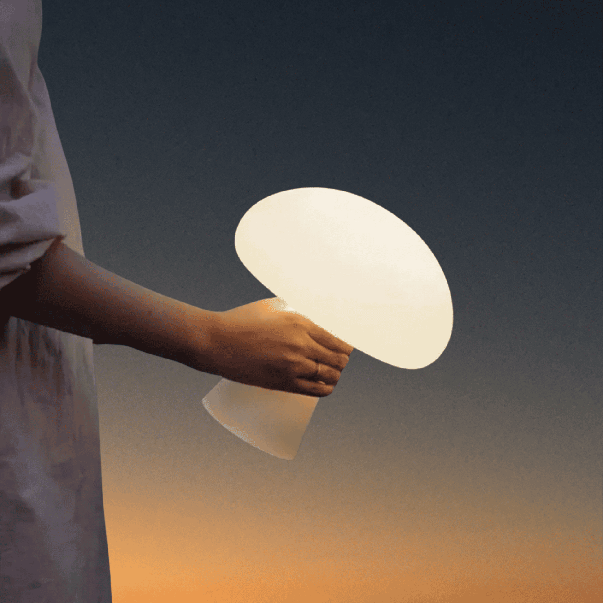 Person holding a glowing white lamp against a dark sky with a sunset gradient.