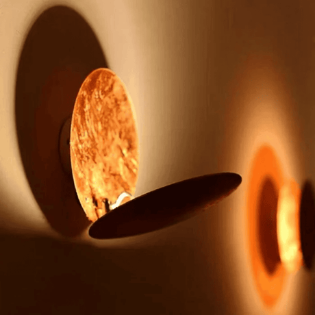 Moon Eclipse LED Wall Light casting warm glow on wall. Adjustable sconce creates elegant ambiance in corridor or bedroom lighting.