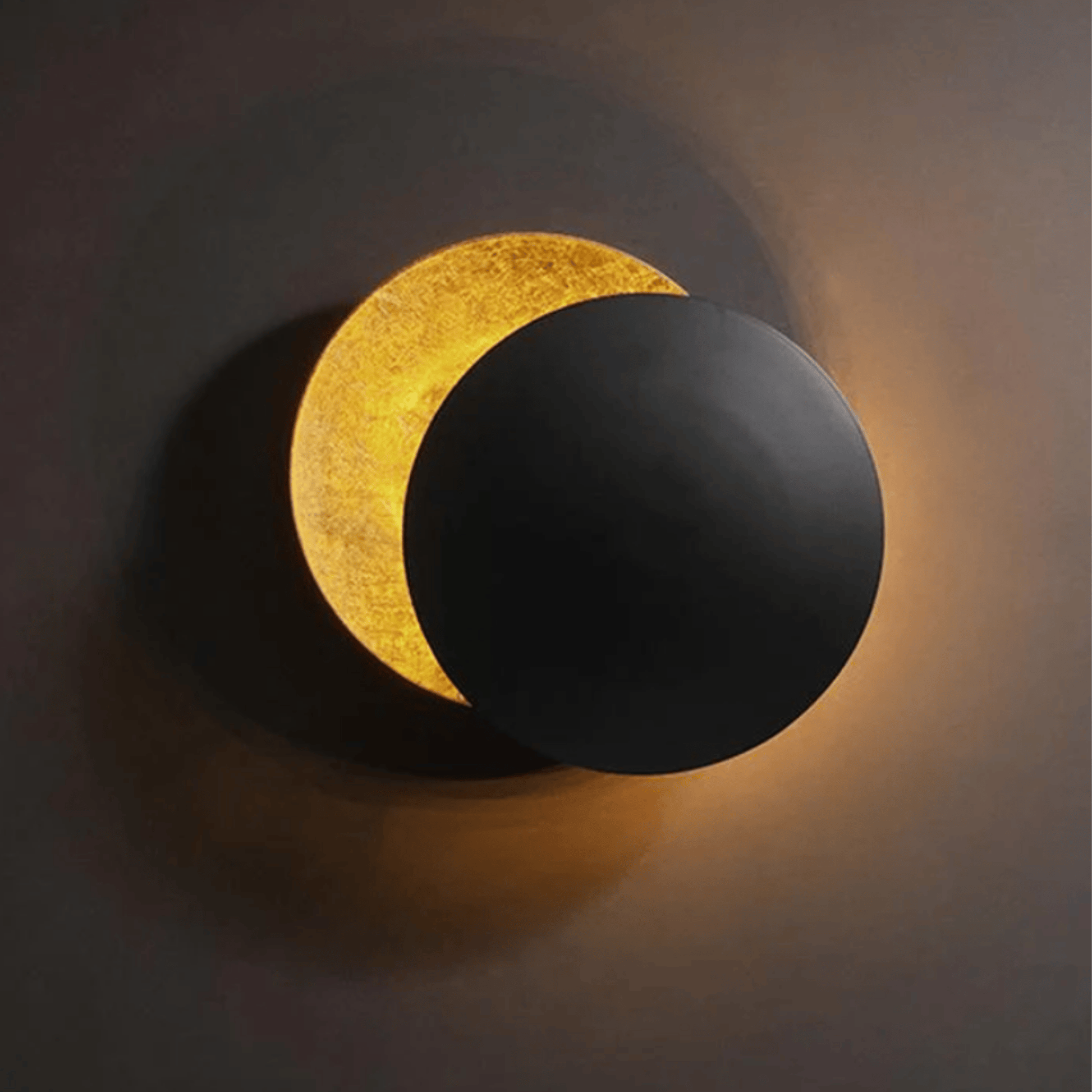 Elegant Moon Eclipse LED Sconce with adjustable black disc revealing golden backlight. Perfect for creating cozy ambiance in home spaces.