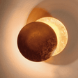 Golden-toned Moon Eclipse LED Wall Light glowing warmly. Ideal for enhancing ambiance in modern home lighting setups.