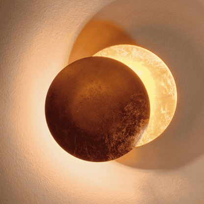 Golden-toned Moon Eclipse LED Wall Light glowing warmly. Ideal for enhancing ambiance in modern home lighting setups.