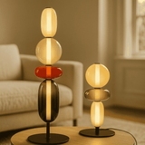 Modern table lamps with stacked glass shades on a wooden table in a living room setting.

