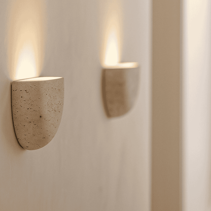 Wall-mounted natural stone sconce emitting soft light in a modern white corridor.