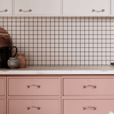 Kitchen with pink cabinets, white countertop, and grid-patterned backsplash.