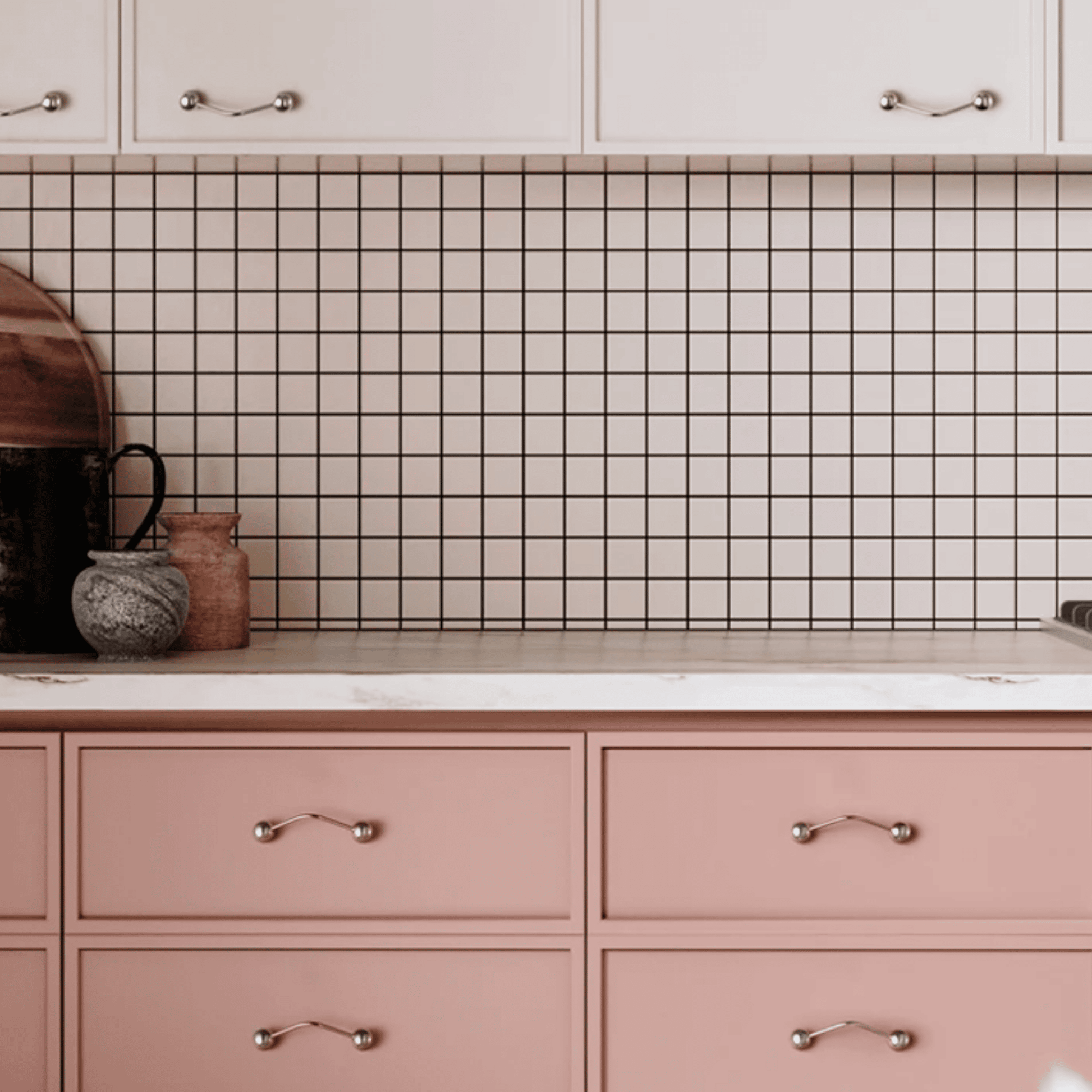 Kitchen with pink cabinets, white countertop, and grid-patterned backsplash.