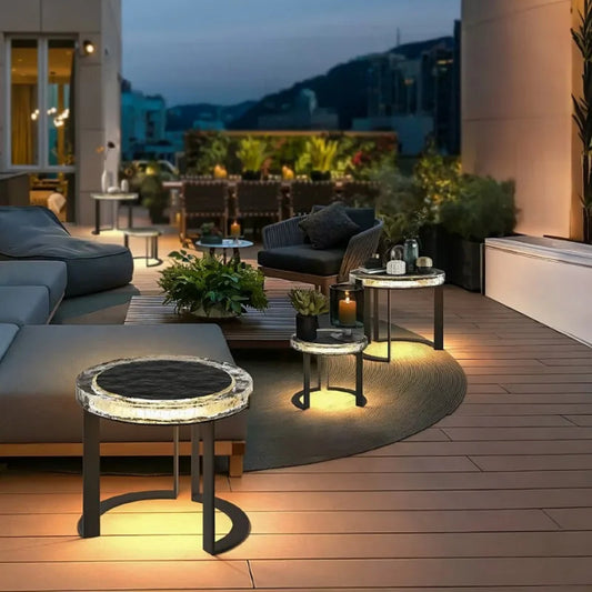 Modern outdoor patio with furniture and lighting, overlooking a cityscape at night.