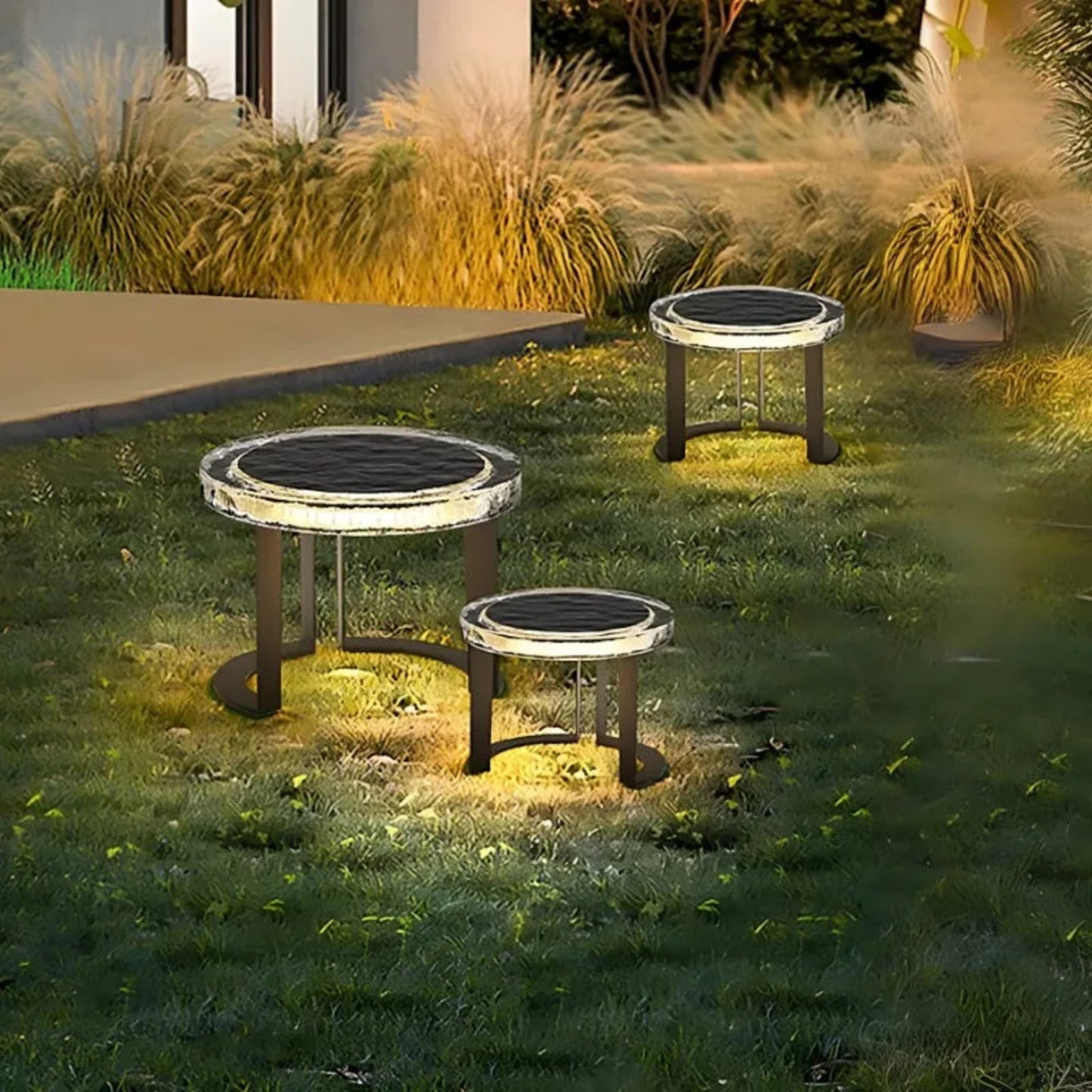 Three solar-powered garden lights on grass with a house in the background