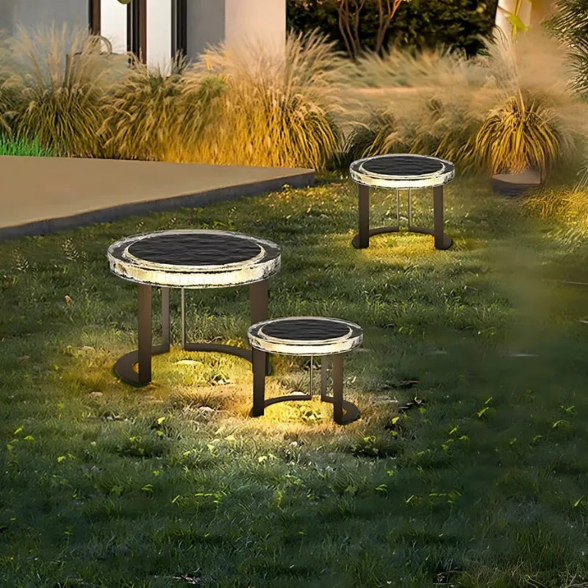 Three solar-powered garden lights on grass with a house in the background