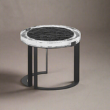 Small round table with black marble top and black metal base on a beige background