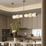 Modern kitchen with a chandelier, vase with flowers, and kitchen appliances.
