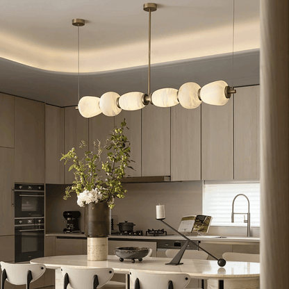 Modern kitchen with a chandelier, vase with flowers, and kitchen appliances.