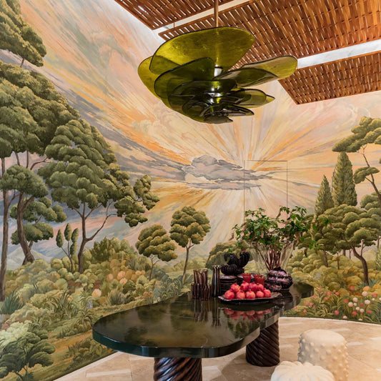 Decorative interior with a mural of a landscape, a ceiling light fixture, and a table with decorative items.