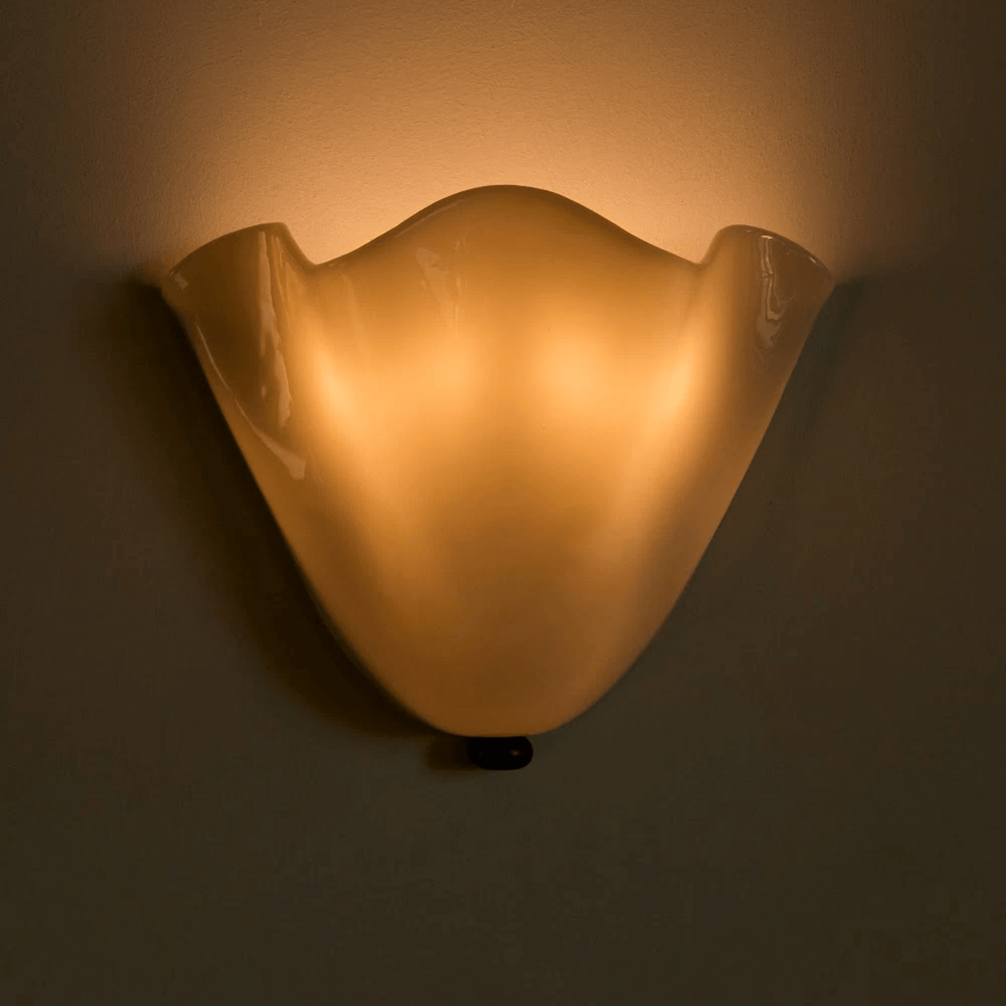 Wall-mounted light fixture casting a warm glow on a plain wall