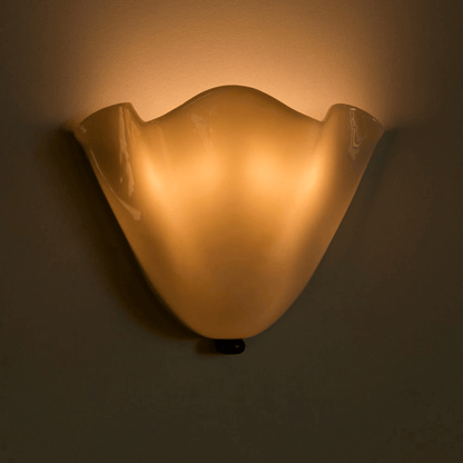 Wall-mounted light fixture casting a warm glow on a plain wall