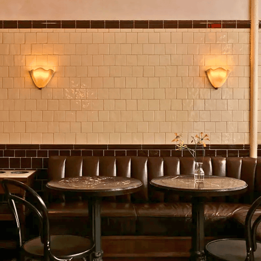 Restaurant interior with tiled walls, leather booths, and round tables.