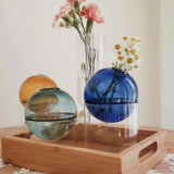 Decorative glass spheres on a wooden tray with flowers in the background
