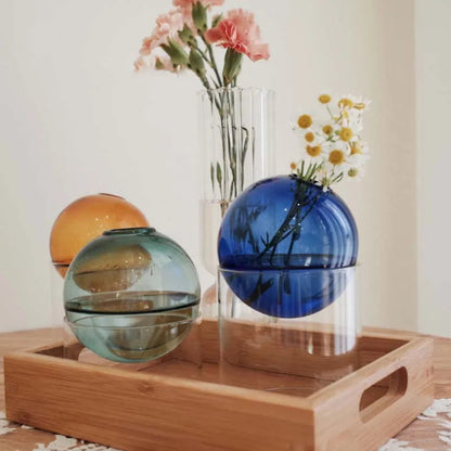 Decorative glass spheres on a wooden tray with flowers in the background