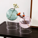 Two glass vases with floral arrangements on a dark surface.
