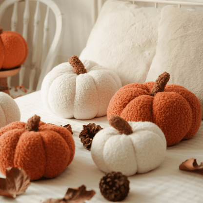 Decorative pumpkins in orange and white on a soft surface with pinecones.