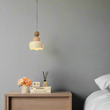 Neatly arranged bedroom with a lamp, books, and flowers on a nightstand.