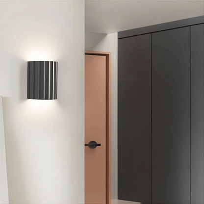 Modern wall lamp on a white wall with a door and wardrobe in the background