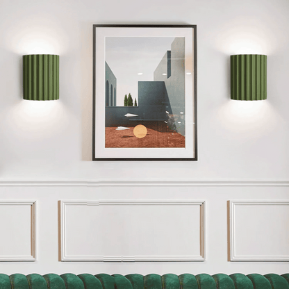 Framed abstract art piece on a wall with two green wall lamps.