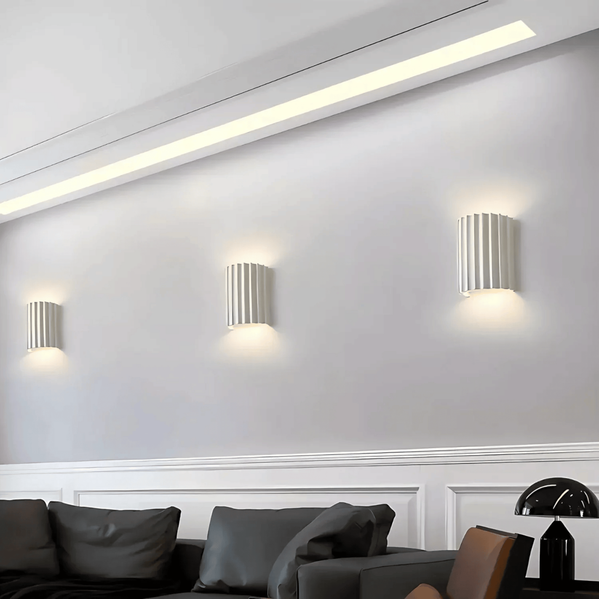Modern wall lights on a white wall with a sofa and decorative items in the foreground.