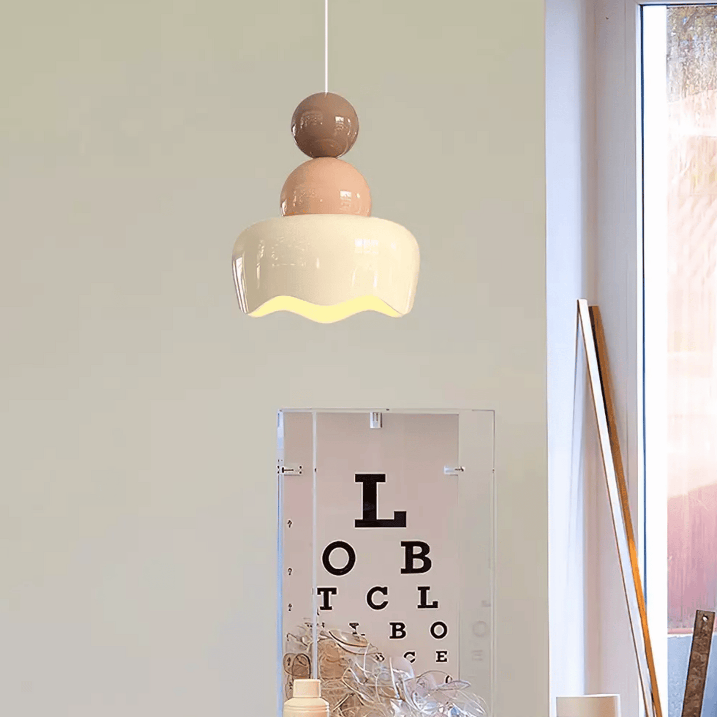 Modern pendant light hanging above a mirror with an eye chart, in a room setting.