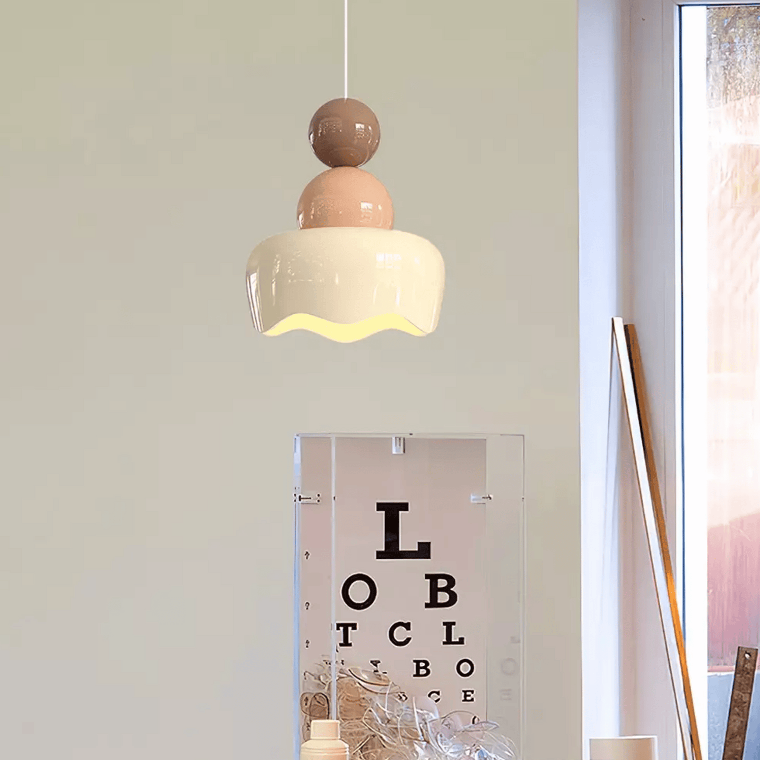 Modern pendant light hanging above a mirror with an eye chart, in a room setting.