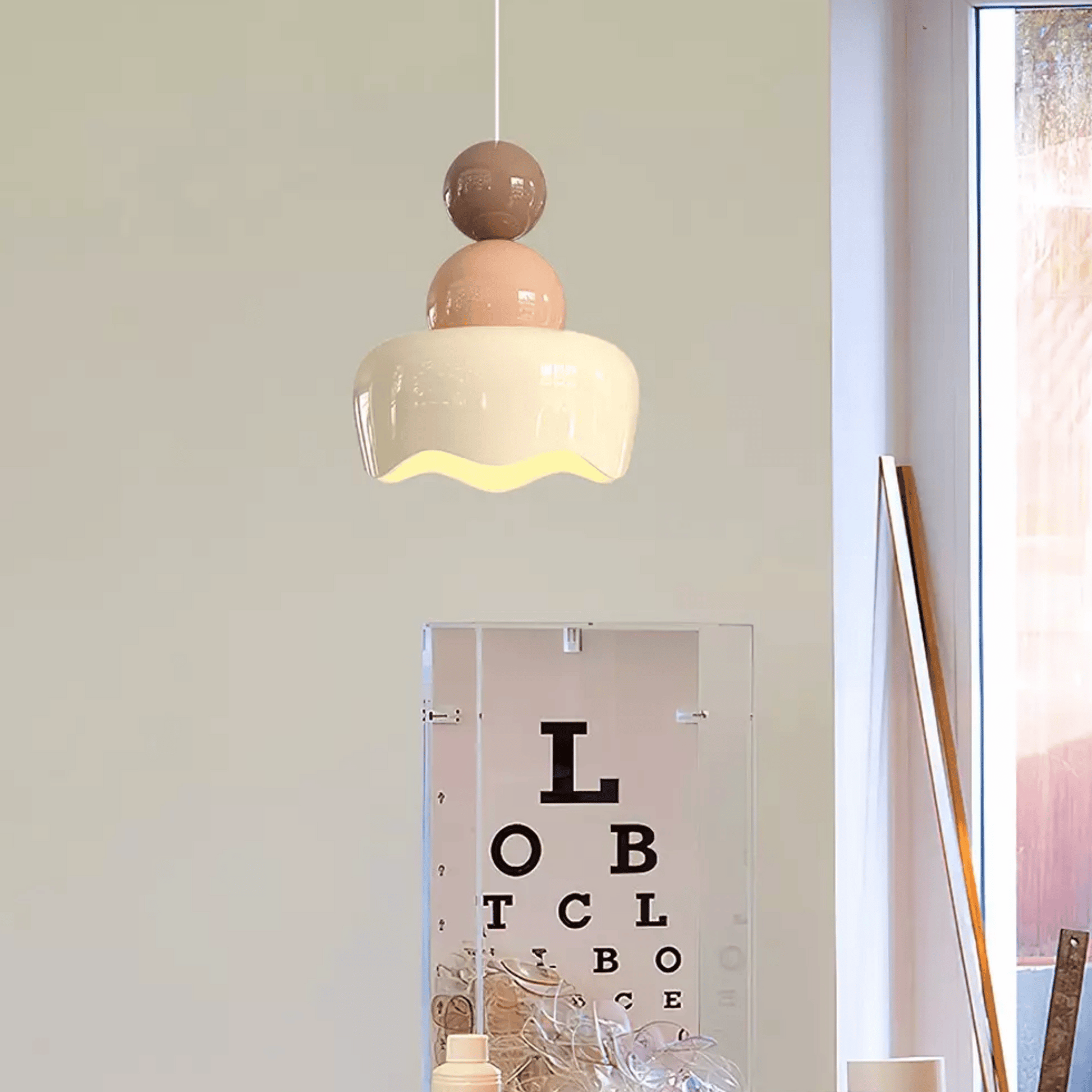 Modern pendant light hanging above a mirror with an eye chart, in a room setting.