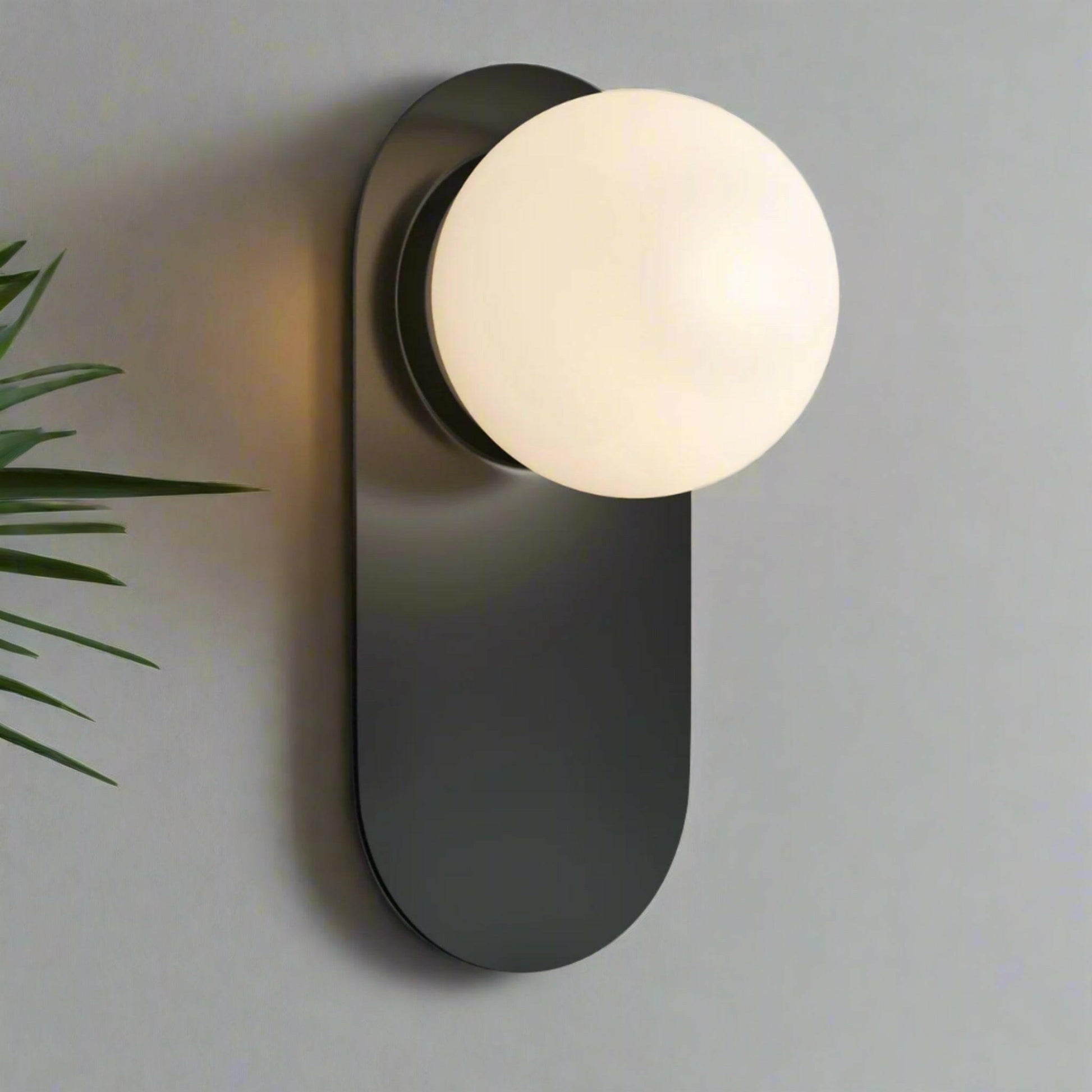 Modern wall sconce with a black fixture and white bulb on a light gray background.