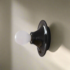 Black wall light fixture with a white bulb on a light gray background