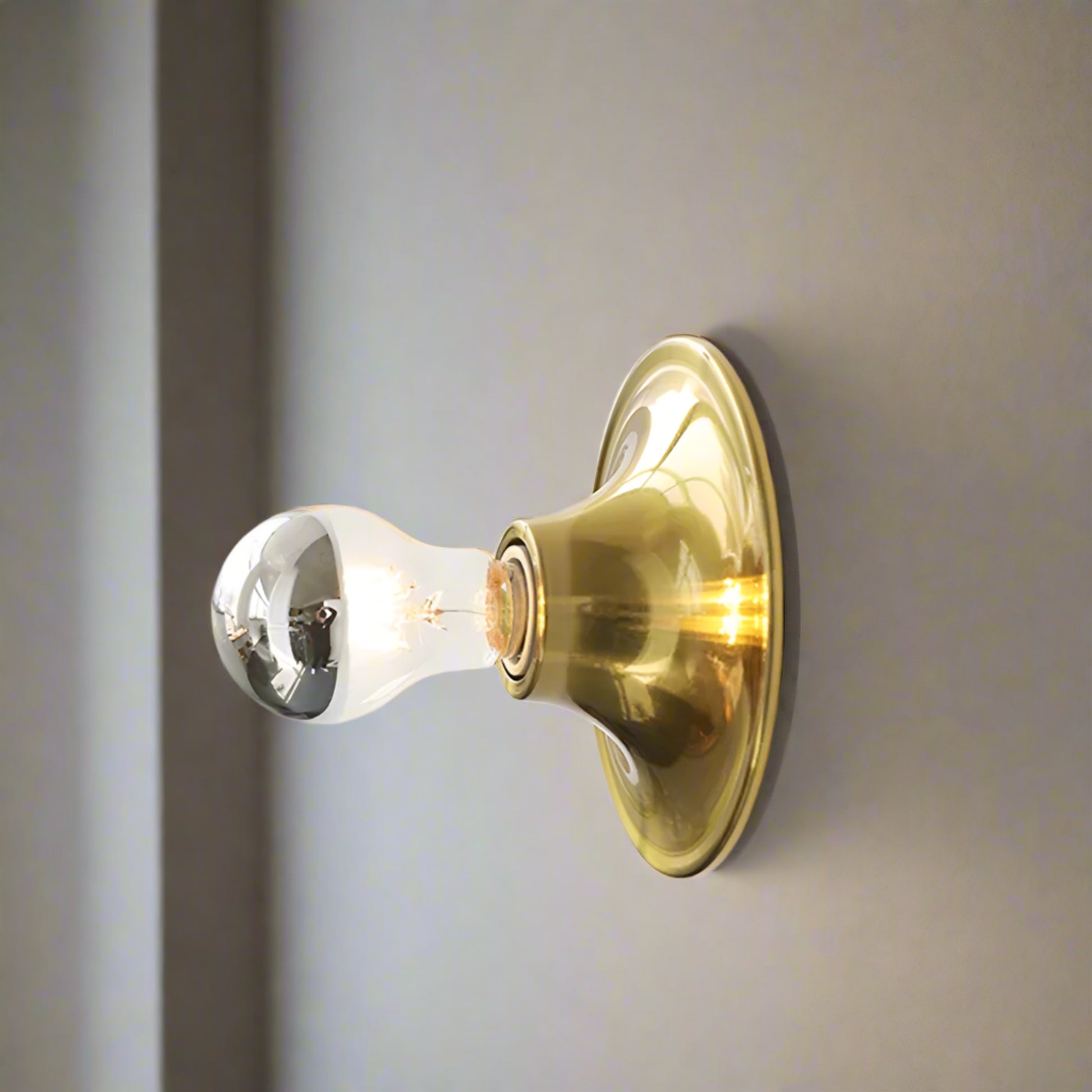 Gold wall light fixture on a white wall with 'Gold' label above.