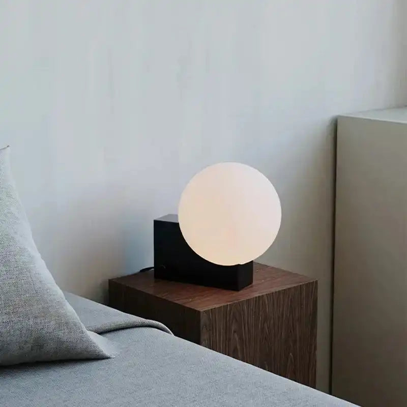 Minimalist dimmable LED bedside lamp with a frosted glass globe and black base. Enhances bedroom ambiance with soft lighting.