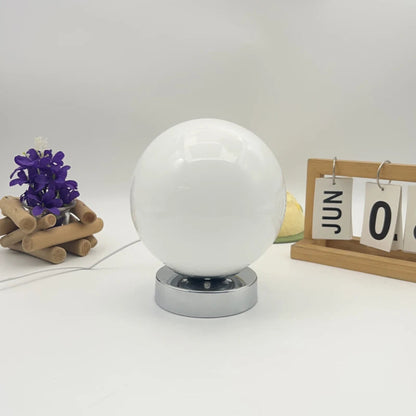 White crystal ball on a stand with decorative items on a white background