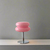 Pink stool on a wooden surface with decorative items against a white wall