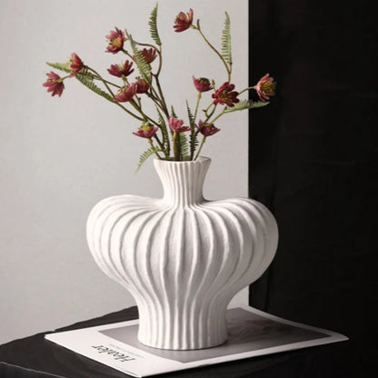 White textured vase with floral arrangement on a dark surface