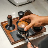 Hand using a coffee grinder on a wooden stand with a blurred background