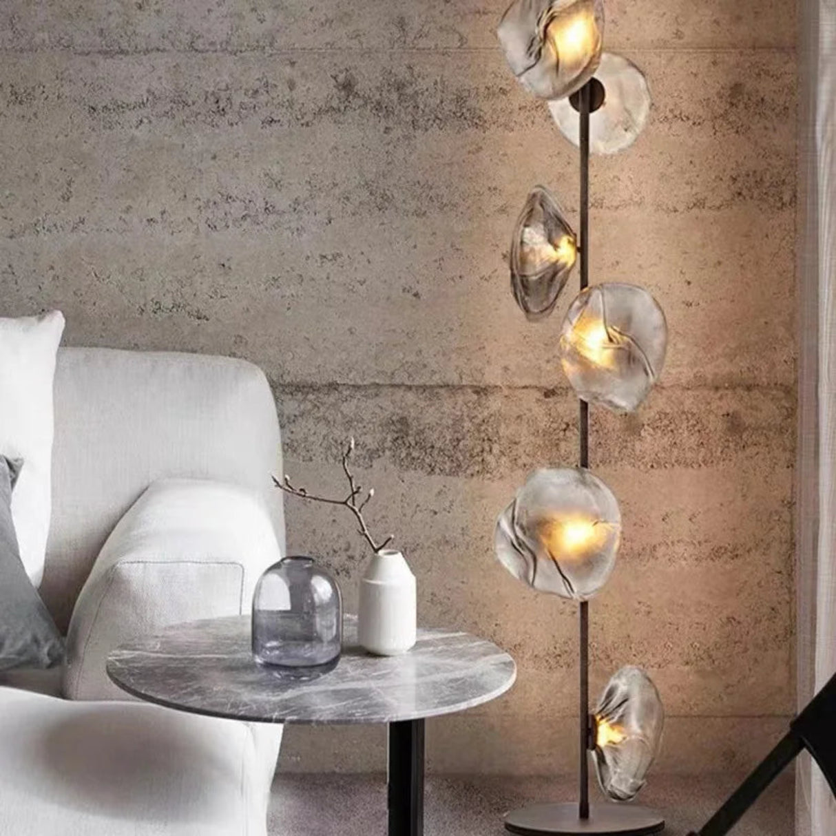 Modern interior with a floor lamp, table, and sofa against a textured wall.