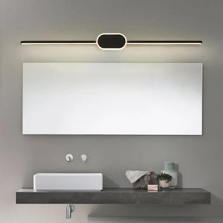 Modern bathroom setup with a large mirror, light fixture, sink, and decorative items.
