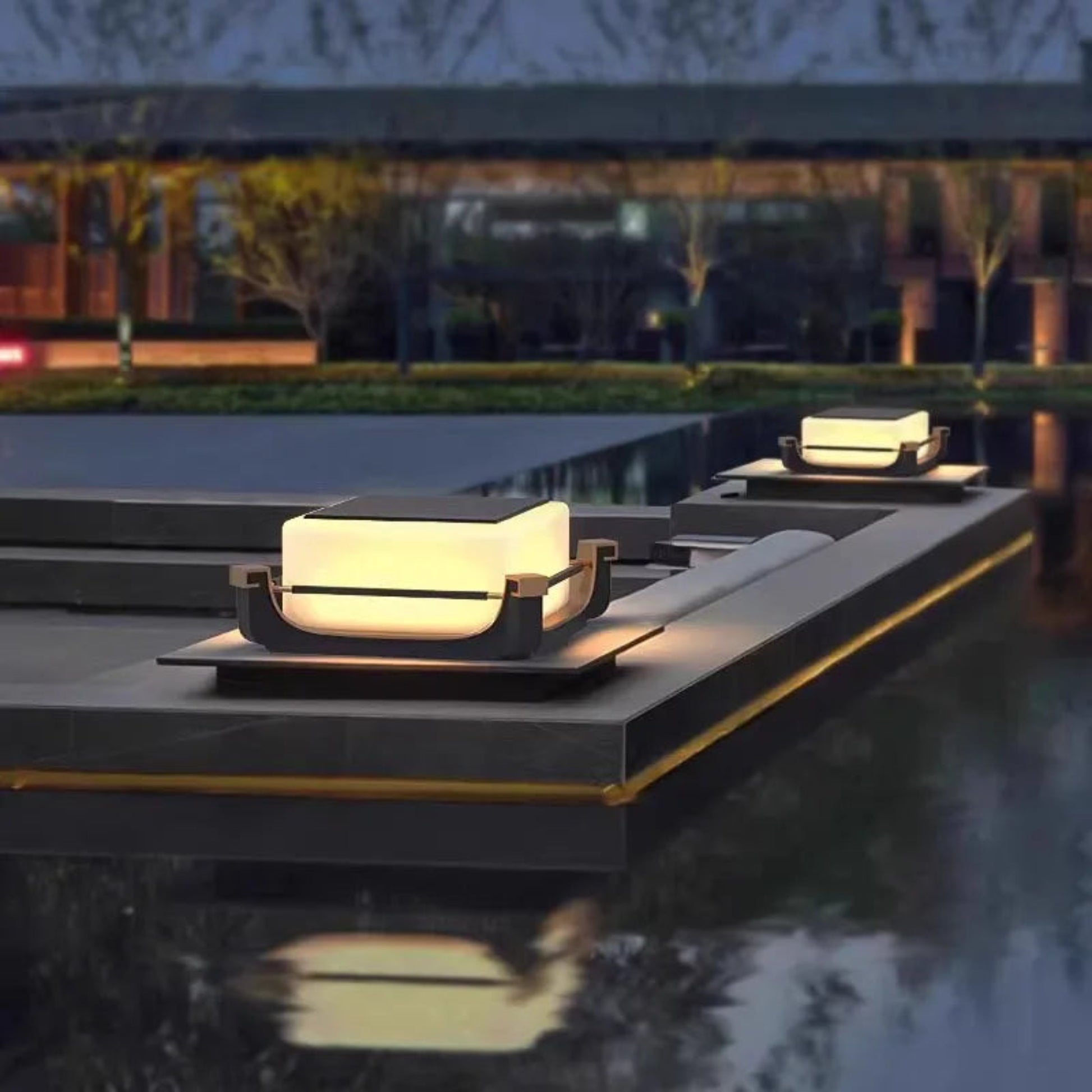 Modern outdoor lighting fixtures on stone steps near a body of water at night.