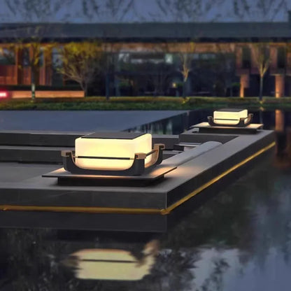 Modern outdoor lighting fixtures on stone steps near a body of water at night.