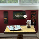 Decorative table with magazine and lamp against a red wall with framed pictures