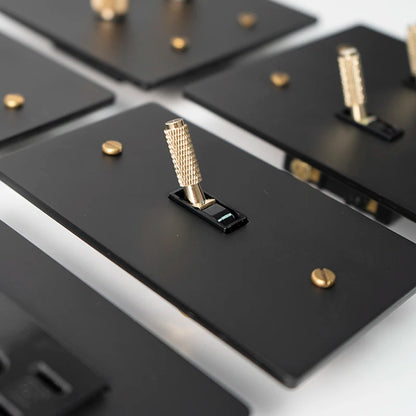 Close-up of black metal brackets with gold screws on a reflective surface