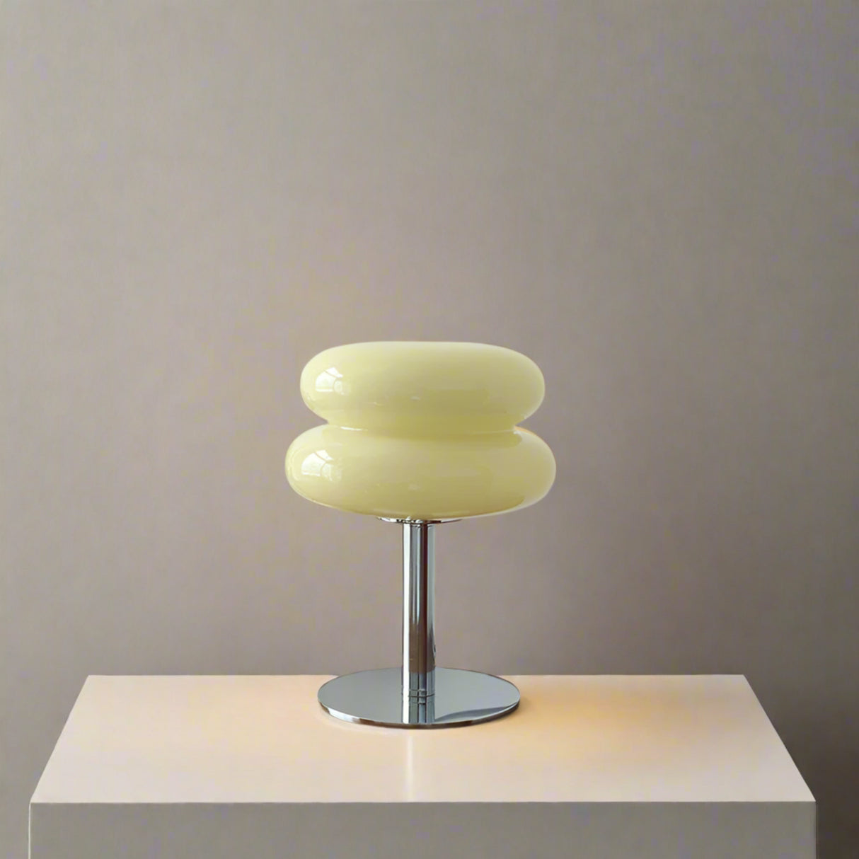 Yellow table lamp on a wooden surface with decorative items against a white wall