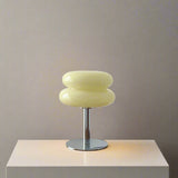 Yellow table lamp on a wooden surface with decorative items against a white wall